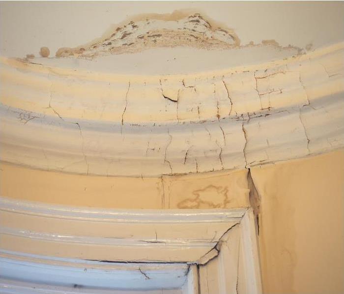 visible cracks in a beige colored wall and ceiling  due to water damage